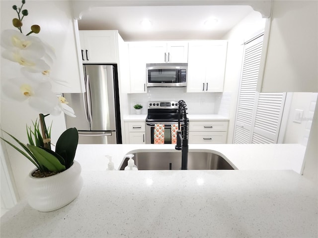 2935 Lichen Ln Unit D, Clearwater, FL 33760 - kitchen with appliances with stainless steel finishes, white cabinetry, decorative backsplash, and light stone countertops