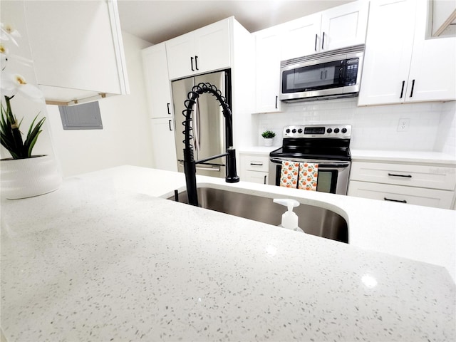 2935 Lichen Ln Unit D, Clearwater, FL 33760 - kitchen featuring appliances with stainless steel finishes, backsplash, white cabinets, and light stone countertops
