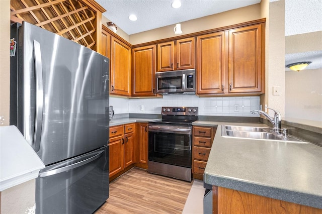 731 Cruise View Dr, Tampa, FL 33602 - kitchen with stainless steel appliances, a sink, brown cabinets, a textured ceiling, and light wood-type flooring