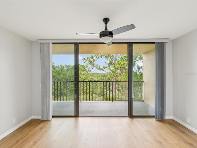 3062 Eastland Blvd Unit 405, Clearwater, FL 33761 - unfurnished room with a wall of windows, wood finished floors, a ceiling fan, and baseboards