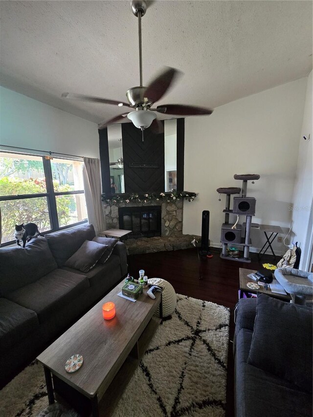 7920 52nd St N, Pinellas Park, FL 33781 - living room featuring a ceiling fan, wood finished floors, a textured ceiling, and a stone fireplace