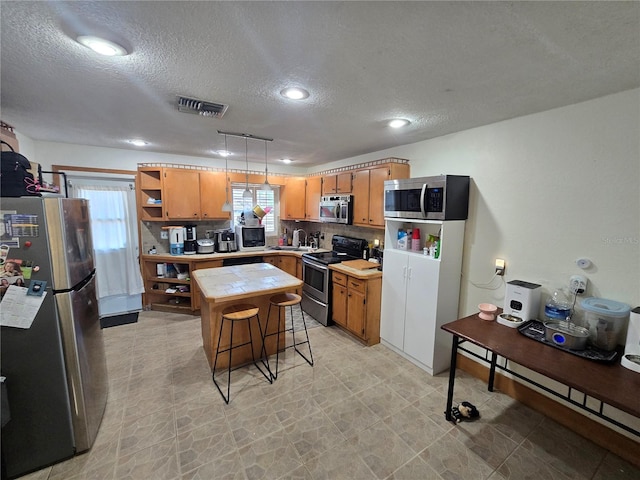 7920 52nd St N, Pinellas Park, FL 33781 - kitchen with appliances with stainless steel finishes, open shelves, a textured ceiling, a center island, and backsplash