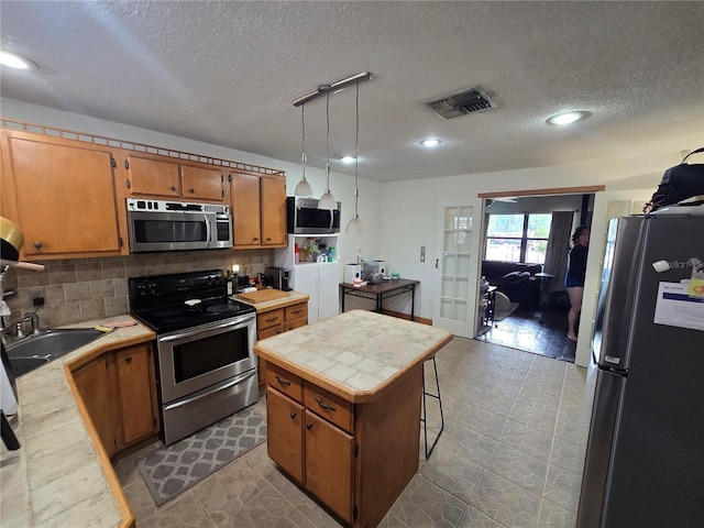 7920 52nd St N, Pinellas Park, FL 33781 - kitchen with appliances with stainless steel finishes, a textured ceiling, brown cabinetry, tile counters, and a sink