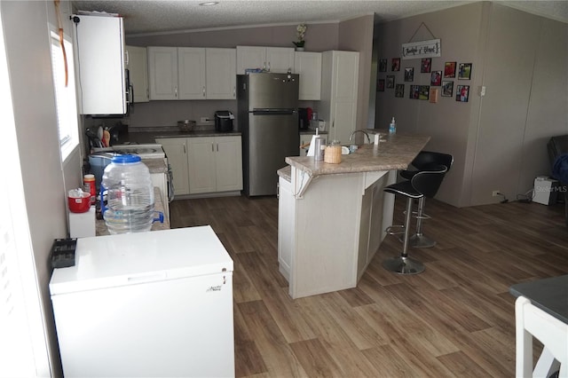 12008 Rose Ln, Riverview, FL 33569 - kitchen with freestanding refrigerator, white fridge, white cabinets, a textured ceiling, and wood finished floors