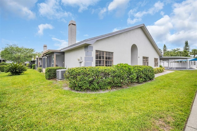 2749 Countryside Blvd Unit 20, Clearwater, FL 33761 - view of home's exterior with central AC unit, a chimney, a lawn, and stucco siding