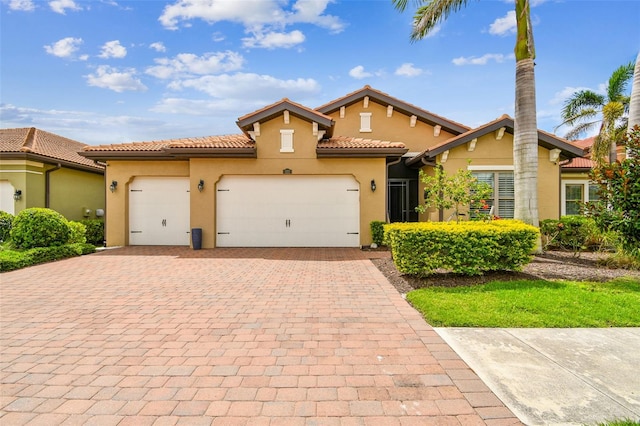 222 Toscavilla Blvd, Nokomis, FL 34275 - mediterranean / spanish house with stucco siding, decorative driveway, an attached garage, and a tile roof