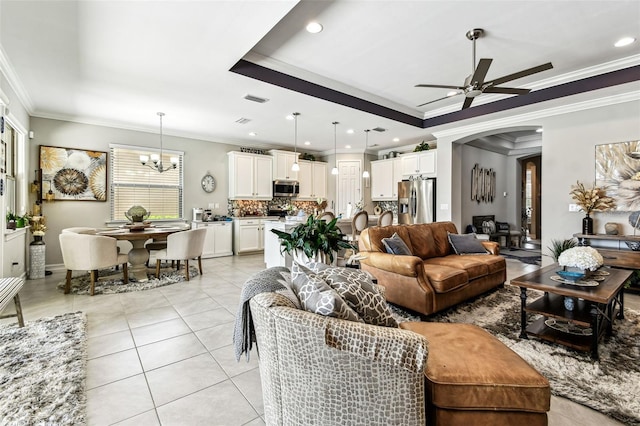 222 Toscavilla Blvd, Nokomis, FL 34275 - living room featuring ornamental molding, a ceiling fan, a chandelier, a tray ceiling, and arched walkways