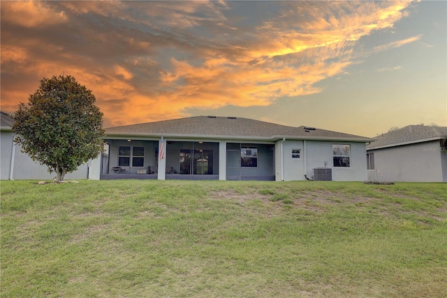 3813 Salida Delsol Dr, Sun City Center, FL 33573 - back of property at dusk featuring a lawn, central AC, stucco siding, and a sunroom
