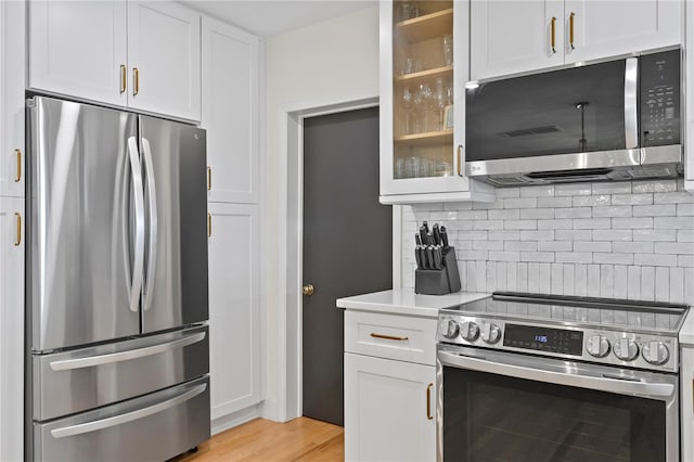 125 Live Oak Ln, Largo, FL 33770 - kitchen featuring stainless steel appliances, glass insert cabinets, tasteful backsplash, light countertops, and white cabinetry