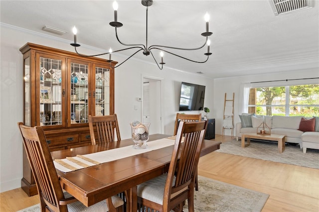 125 Live Oak Ln, Largo, FL 33770 - dining space featuring light wood-style floors, crown molding, and a chandelier