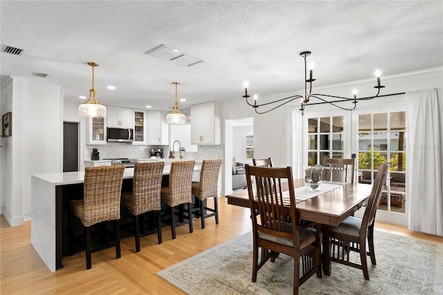 125 Live Oak Ln, Largo, FL 33770 - dining area featuring light wood-style floors, a chandelier, and a textured ceiling