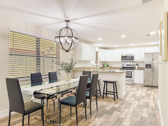 1025 Reading Rd, Lutz, FL 33558 - dining area with a chandelier, light wood-style flooring, healthy amount of natural light, a textured ceiling, and recessed lighting