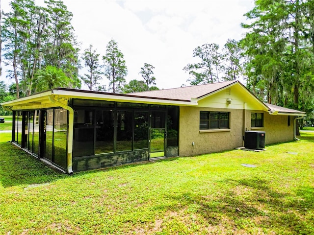 1025 Reading Rd, Lutz, FL 33558 - back of property featuring central air condition unit, a sunroom, stucco siding, and a lawn