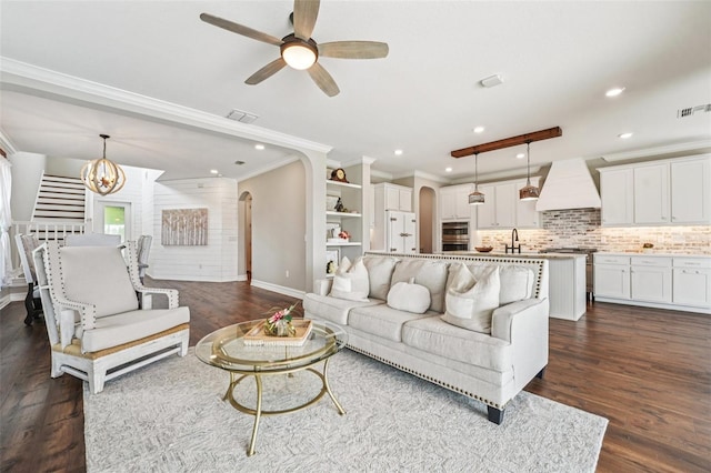 19191 Pease Pl, Lutz, FL 33558 - living room with arched walkways, dark wood-style flooring, crown molding, a chandelier, and a ceiling fan