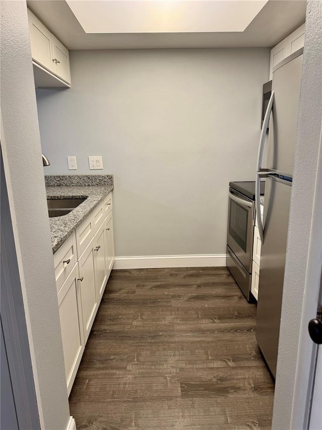 3802 N Oak Dr Unit W22, Tampa, FL 33611 - kitchen featuring appliances with stainless steel finishes, dark wood-style flooring, light stone counters, a sink, and white cabinets