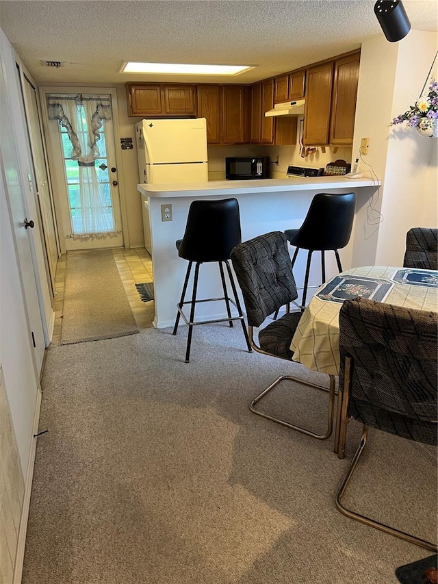 7616 Colonial Ct, Tampa, FL 33615 - kitchen featuring freestanding refrigerator, black microwave, a textured ceiling, a peninsula, and light countertops