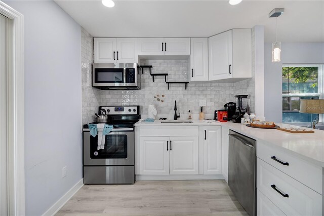 13325 1st St E, Madeira Beach, FL 33708 - kitchen featuring stainless steel appliances, a sink, tasteful backsplash, light countertops, and white cabinetry
