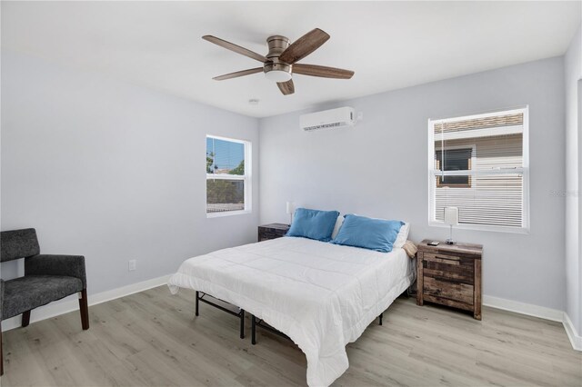 13325 1st St E, Madeira Beach, FL 33708 - bedroom with an AC wall unit, light wood-style floors, baseboards, and ceiling fan