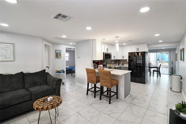 13800 Judy Ave, Hudson, FL 34667 - kitchen featuring black fridge, a peninsula, stainless steel microwave, open floor plan, and a kitchen breakfast bar