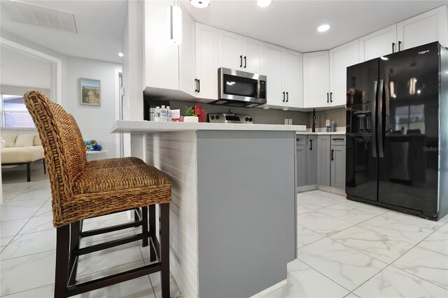 13800 Judy Ave, Hudson, FL 34667 - kitchen featuring black refrigerator with ice dispenser, stainless steel microwave, light marble finish floors, white cabinets, and recessed lighting