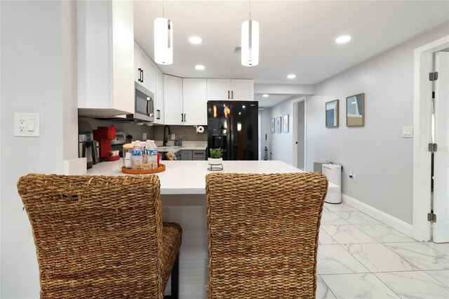 13800 Judy Ave, Hudson, FL 34667 - kitchen with black fridge with ice dispenser, a peninsula, stainless steel microwave, light marble finish flooring, and light countertops