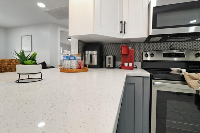 13800 Judy Ave, Hudson, FL 34667 - kitchen with stainless steel appliances, white cabinets, light stone countertops, and speckled floor