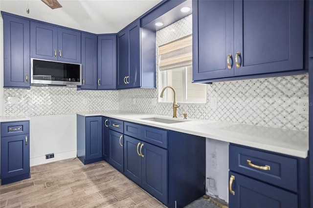 403 Normandy Rd, Madeira Beach, FL 33708 - kitchen with stainless steel microwave, a sink, light wood-type flooring, and blue cabinets