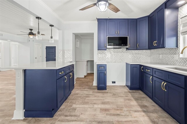 403 Normandy Rd, Madeira Beach, FL 33708 - kitchen featuring a ceiling fan, blue cabinetry, stainless steel microwave, a sink, and light wood-style floors