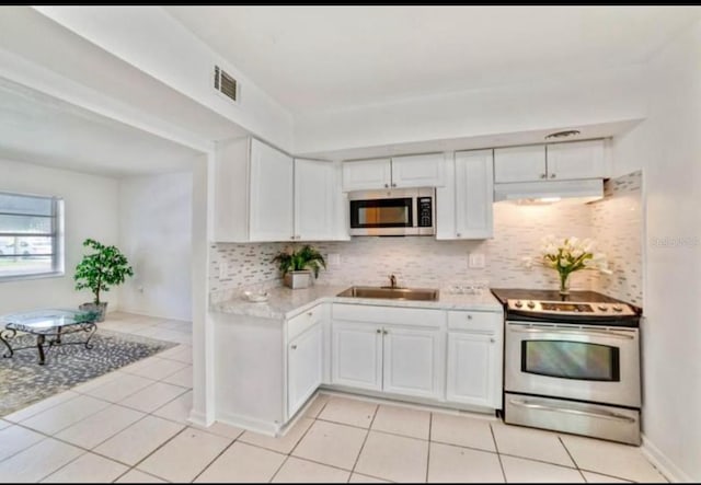 7313 Royal Palm Dr, New Port Richey, FL 34652 - kitchen featuring stainless steel appliances, a sink, light countertops, under cabinet range hood, and decorative backsplash