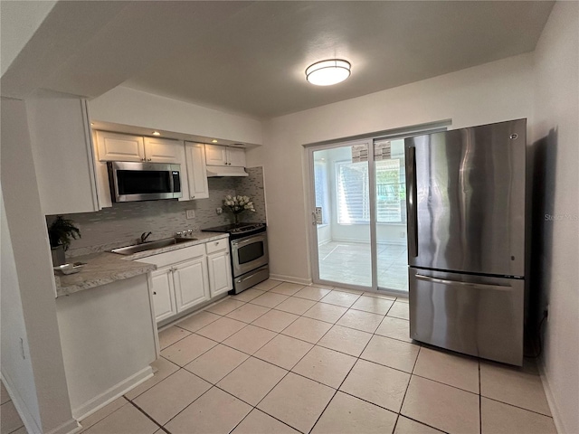 7313 Royal Palm Dr, New Port Richey, FL 34652 - kitchen featuring stainless steel appliances, tasteful backsplash, light countertops, white cabinetry, and light tile patterned floors