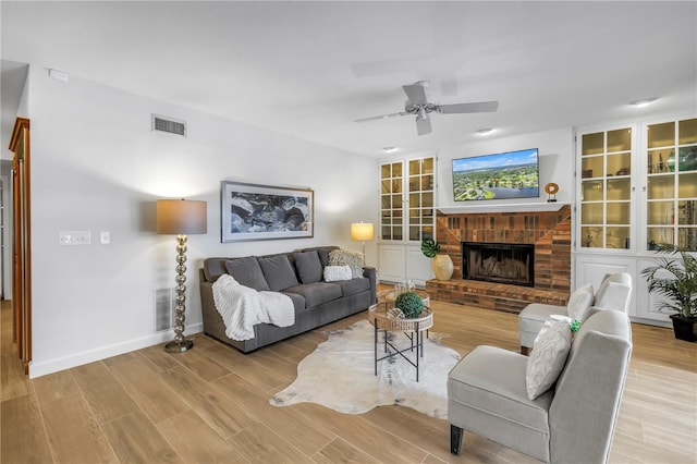 8127 Siquita Dr NE, Saint Petersburg, FL 33702 - living area with a ceiling fan, wood finished floors, a brick fireplace, and baseboards