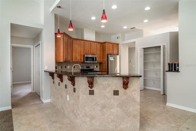 14266 Creek Run Dr, Riverview, FL 33579 - kitchen featuring appliances with stainless steel finishes, brown cabinetry, a kitchen breakfast bar, dark stone counters, and a peninsula