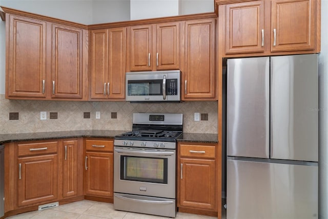 14266 Creek Run Dr, Riverview, FL 33579 - kitchen featuring stainless steel appliances, brown cabinets, dark stone countertops, and decorative backsplash