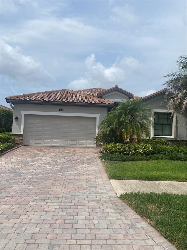 12619 Richezza Dr, Venice, FL 34293 - view of front facade with decorative driveway, a tiled roof, stucco siding, and an attached garage