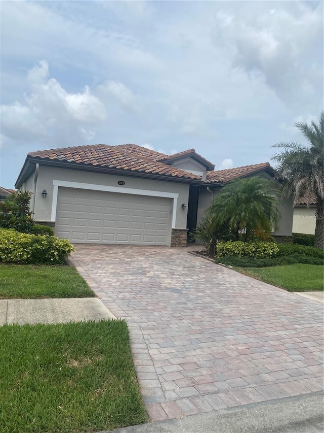 12619 Richezza Dr, Venice, FL 34293 - mediterranean / spanish-style home featuring a tiled roof, stucco siding, and decorative driveway