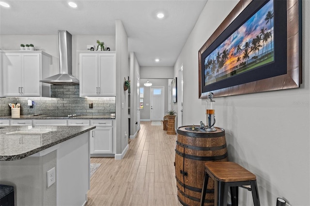31921 Magna Gulf Loop, San Antonio, FL 33576 - kitchen featuring wall chimney exhaust hood, dark stone counters, white cabinetry, decorative backsplash, and recessed lighting