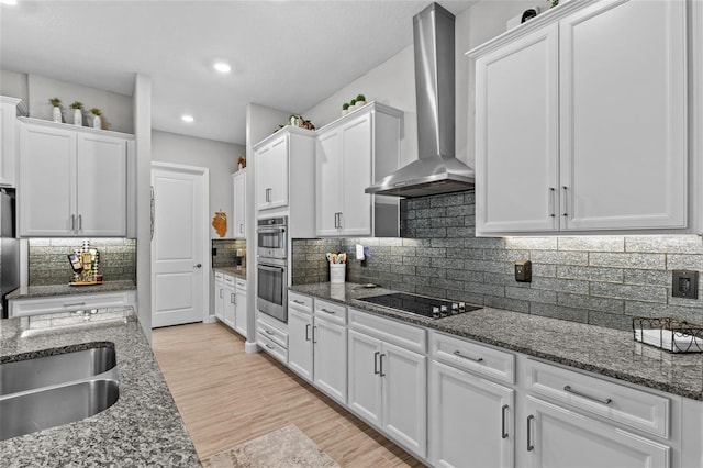 31921 Magna Gulf Loop, San Antonio, FL 33576 - kitchen featuring wall chimney range hood, stainless steel appliances, white cabinets, dark stone countertops, and recessed lighting