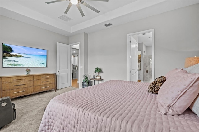 31921 Magna Gulf Loop, San Antonio, FL 33576 - bedroom with light carpet, a tray ceiling, connected bathroom, and ceiling fan