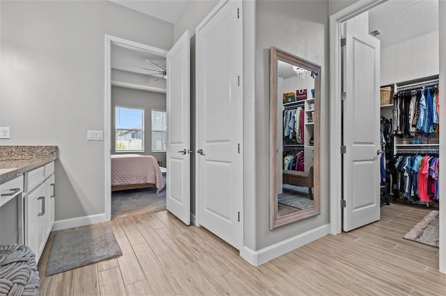 31921 Magna Gulf Loop, San Antonio, FL 33576 - ensuite bathroom with wood finished floors, vanity, ceiling fan, baseboards, and a walk in closet