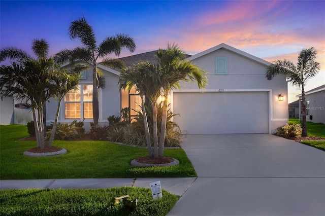 6211 114th Dr E, Parrish, FL 34219 - view of front of house featuring an attached garage, a lawn, stucco siding, and driveway