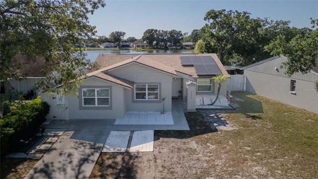 12416 Queensland Ln, Tampa, FL 33625 - view of front of house featuring a shingled roof, solar panels, a water view, stucco siding, and a patio