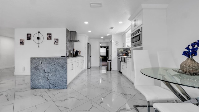 12416 Queensland Ln, Tampa, FL 33625 - kitchen with wall chimney range hood, appliances with stainless steel finishes, recessed lighting, white cabinets, and light marble finish flooring