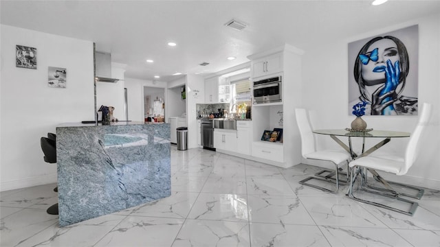 12416 Queensland Ln, Tampa, FL 33625 - kitchen featuring recessed lighting, stainless steel oven, light marble finish floors, white cabinets, and light stone counters