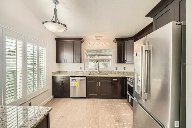 3058 Cara Ct, Palm Harbor, FL 34684 - kitchen with stainless steel appliances, a sink, dark brown cabinets, and light stone counters