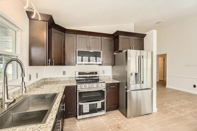 3058 Cara Ct, Palm Harbor, FL 34684 - kitchen with appliances with stainless steel finishes, a sink, dark brown cabinetry, light wood finished floors, and light stone countertops