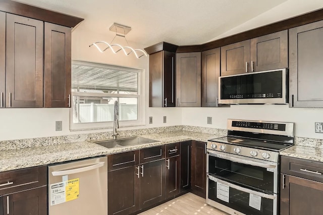 3058 Cara Ct, Palm Harbor, FL 34684 - kitchen with stainless steel appliances, a sink, dark brown cabinets, light stone countertops, and vaulted ceiling