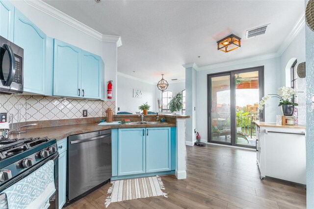 2741 Via Cipriani Unit 934B, Clearwater, FL 33764 - kitchen with stainless steel appliances, blue cabinetry, a peninsula, a sink, and ornamental molding