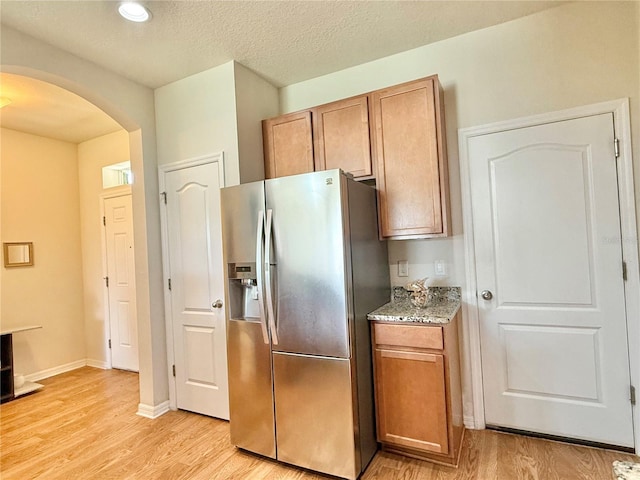 2130 Broadway View Ave, Brandon, FL 33510 - kitchen with stainless steel refrigerator with ice dispenser, arched walkways, light wood-type flooring, and brown cabinets
