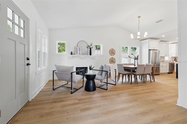 791 44th Ave N, Saint Petersburg, FL 33703 - entrance foyer featuring plenty of natural light, a chandelier, light wood finished floors, vaulted ceiling, and a glass covered fireplace