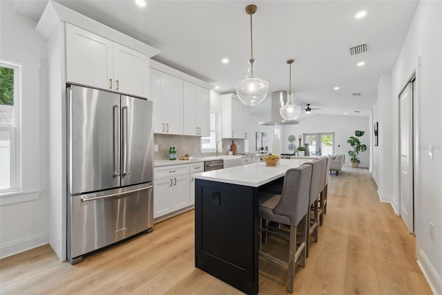 791 44th Ave N, Saint Petersburg, FL 33703 - kitchen featuring stainless steel appliances, light countertops, white cabinets, open floor plan, and light wood-style flooring